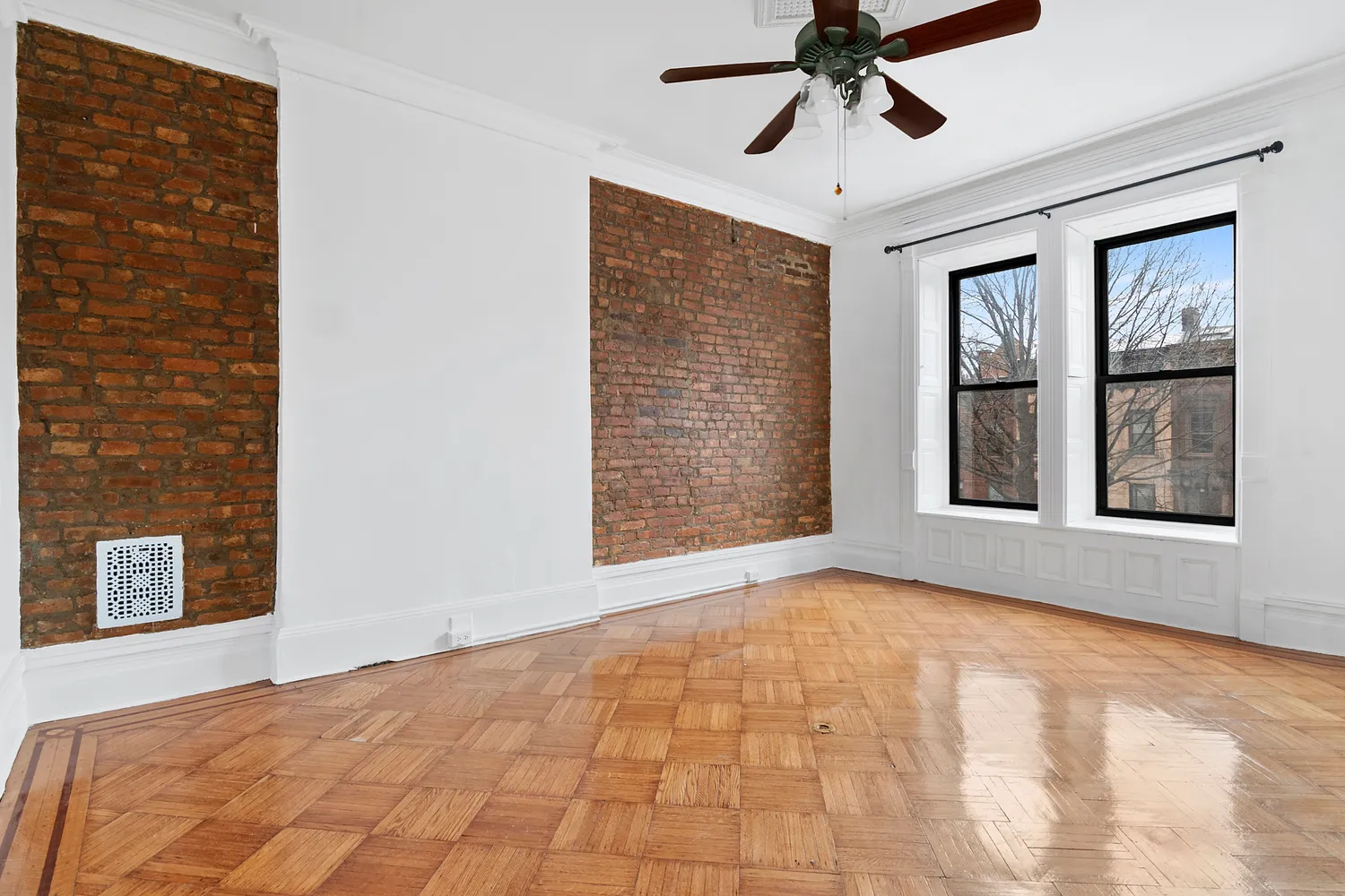 a view of an empty room with a window and chandelier fan