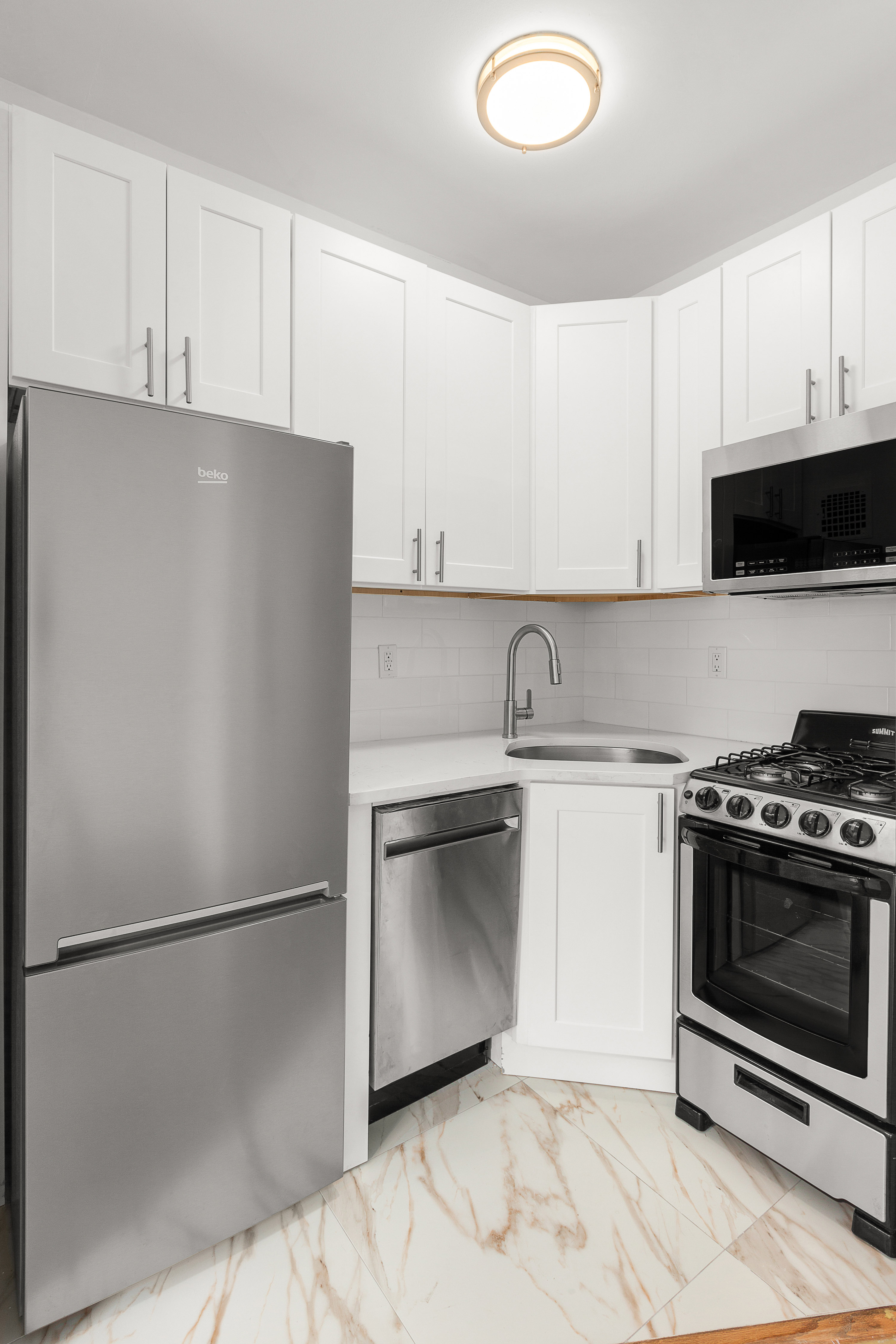 1582 York Avenue, Unit 3A Manhattan, NY 10028 - Photo 2 of 10 a kitchen with a refrigerator stove and white cabinets