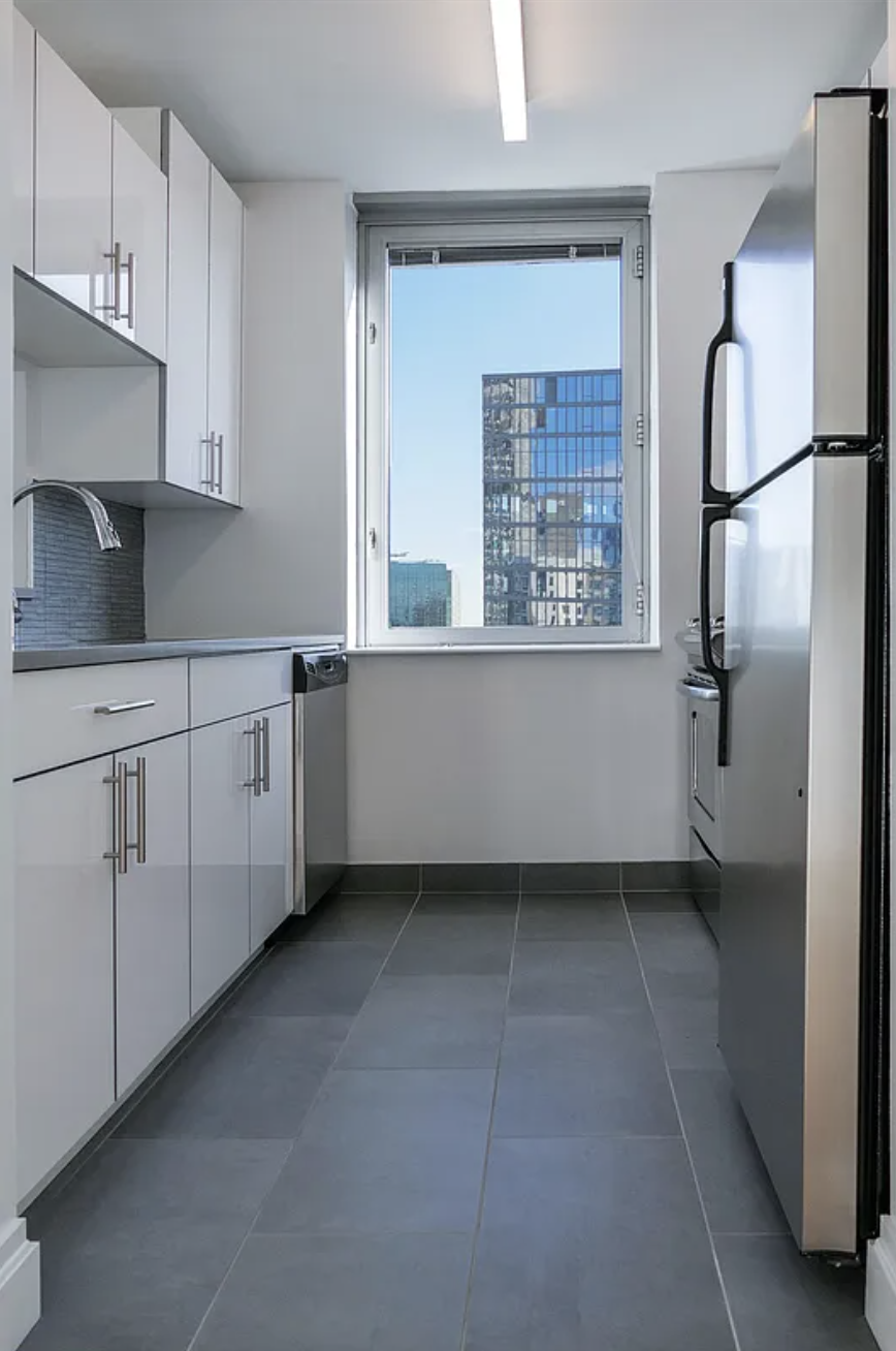 150 East 44th Street, Unit 36C Manhattan, NY 10017 - Photo 3 of 16 a kitchen with a refrigerator a sink and cabinets