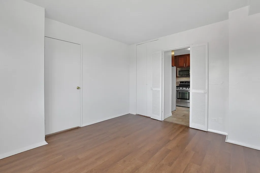 a view of an empty room with wooden floor and closet