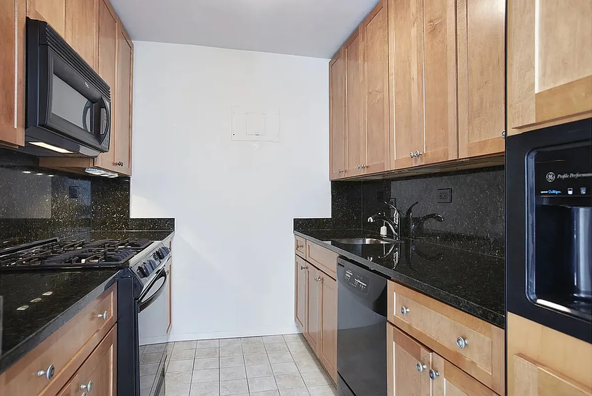 40 East 94th Street, Unit 13G Manhattan, NY 10128 - Photo 8 of 13 a kitchen with stainless steel appliances granite countertop a sink stove and cabinets