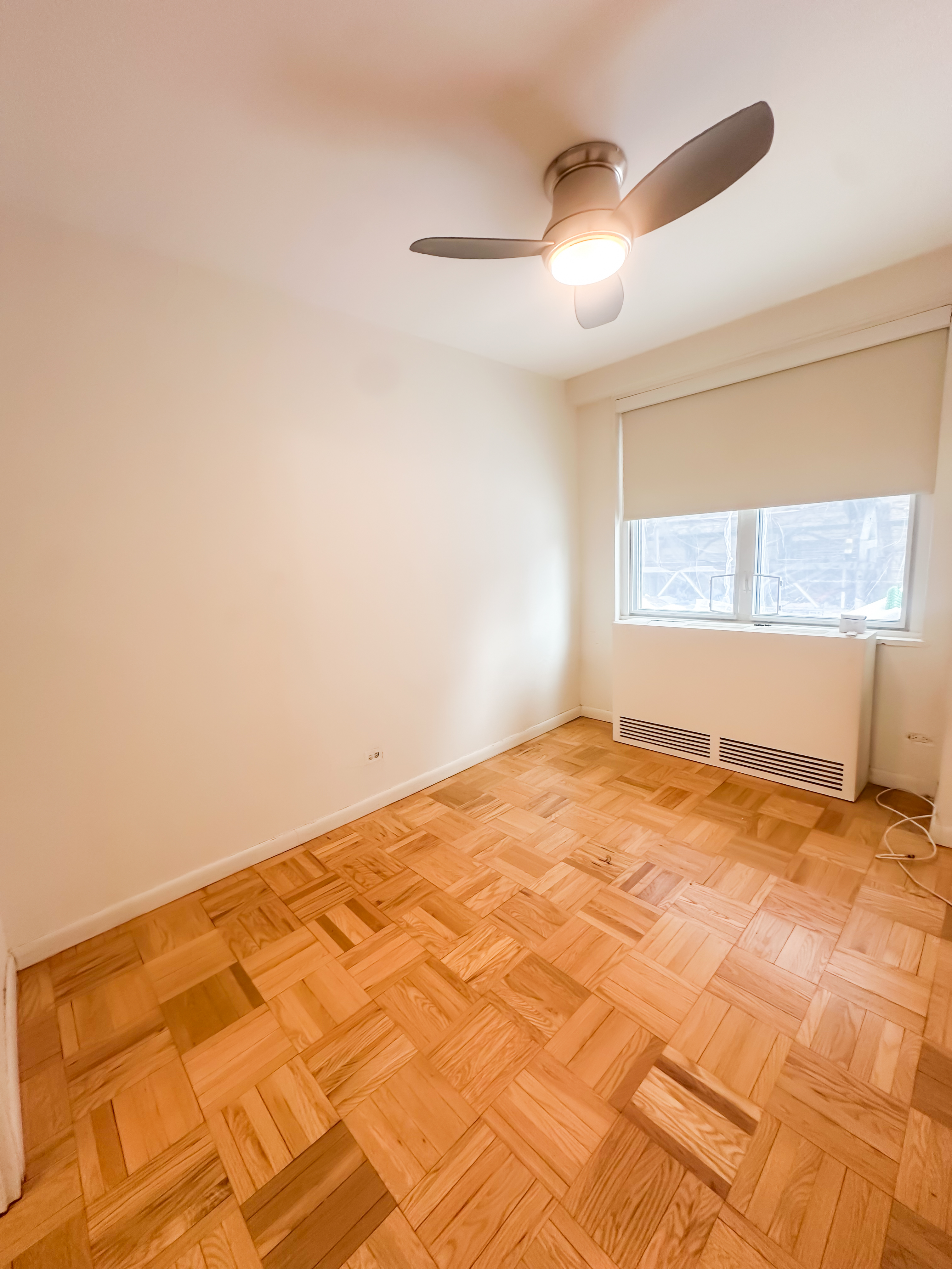 301 East 22nd Street, Unit 2H Manhattan, NY 10010 - Photo 12 of 16 a view of empty room with wooden floor and fan