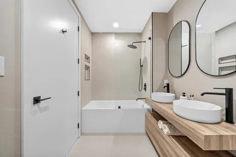 a bathroom with a double vanity sink a mirror and a bathtub