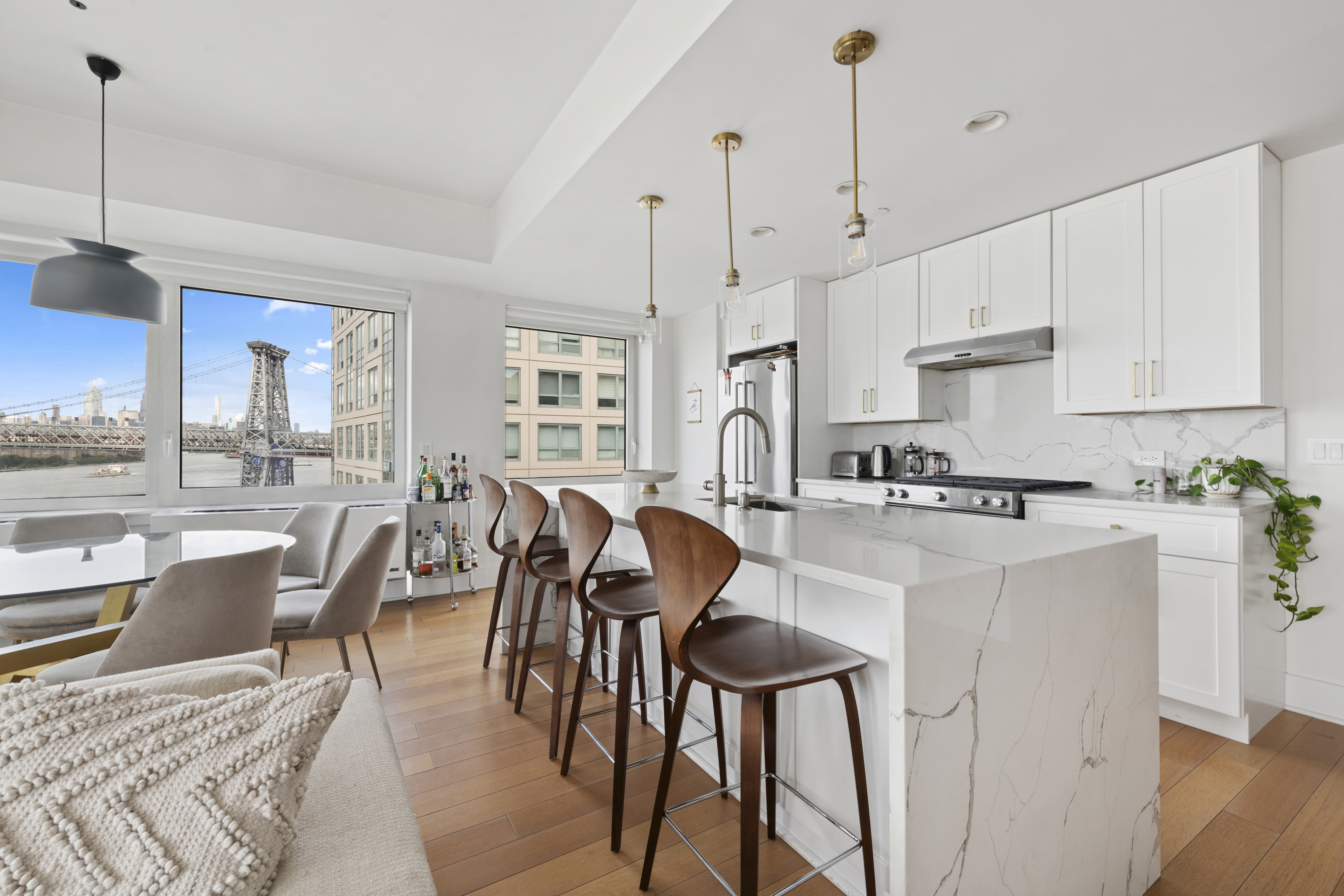 446 Kent Avenue, Unit 14A Brooklyn, NY 11249 - Photo 6 of 19 a kitchen with stainless steel appliances granite countertop a stove a sink a refrigerator a dining table and chairs with wooden floor