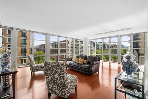 a living room with furniture floor to ceiling window and wooden floor
