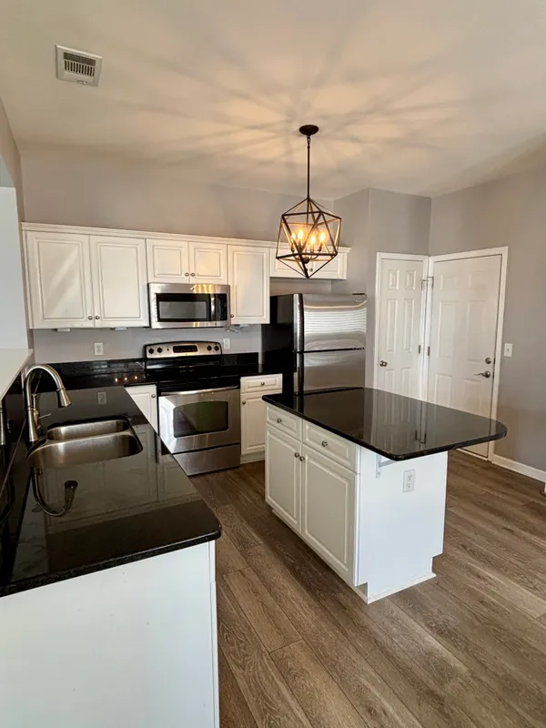 a kitchen with stainless steel appliances a sink a stove a microwave a refrigerator a center island and cabinets