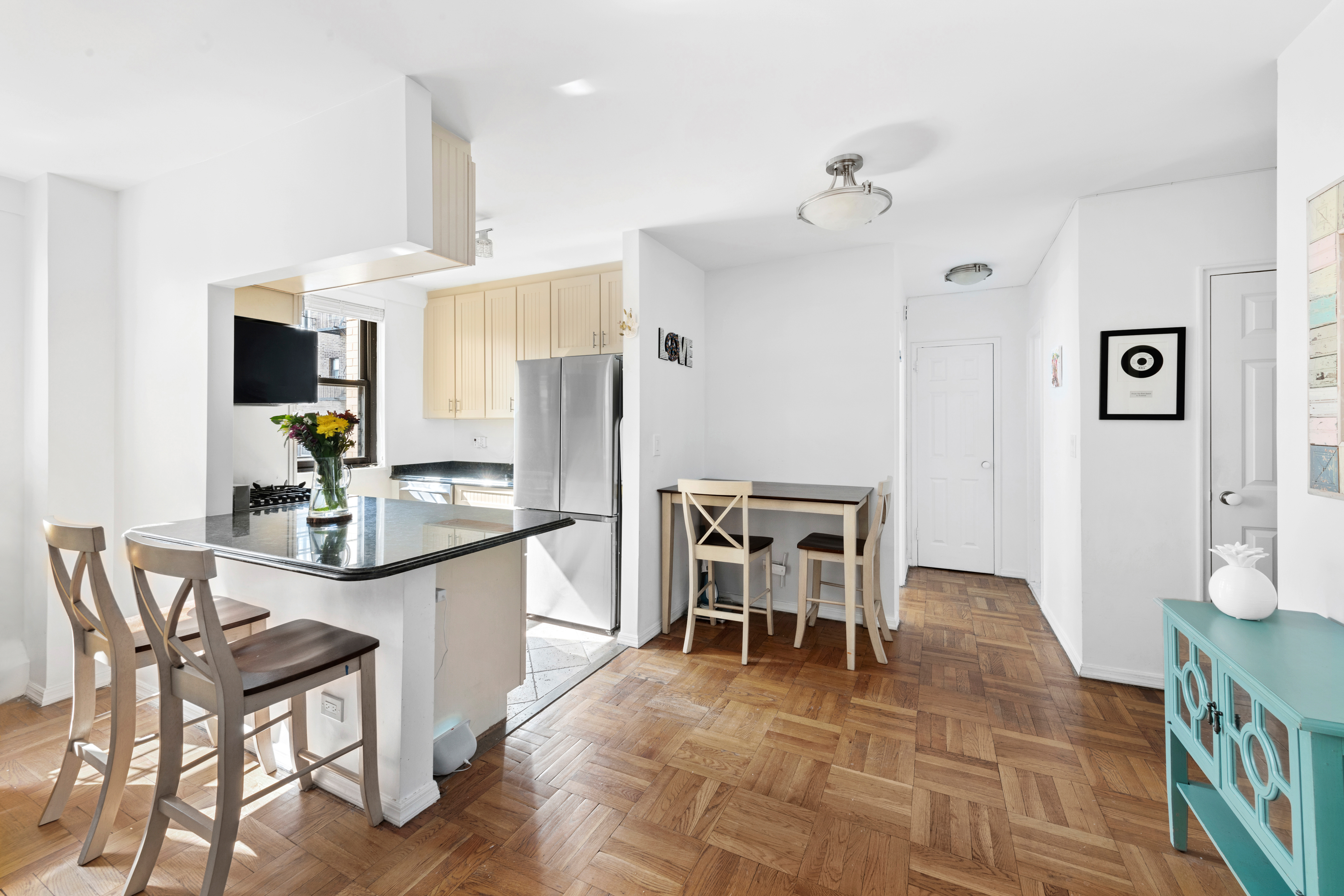 315 East 72nd Street, Unit 15M Manhattan, NY 10021 - Photo 6 of 18 a kitchen with stainless steel appliances a dining table chairs and chandelier