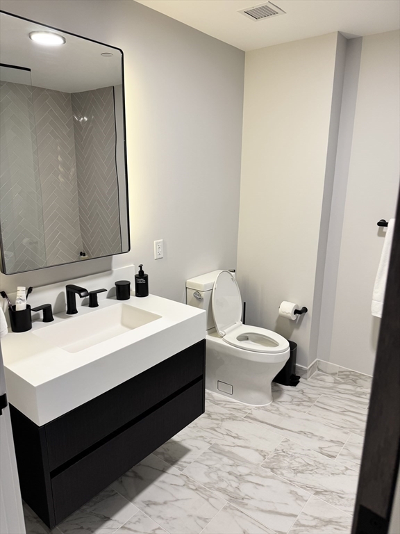55 Lagrange Street, Unit 304 Boston, MA 02111 - Photo 12 of 15 a white toilet sitting next to a bathroom sink