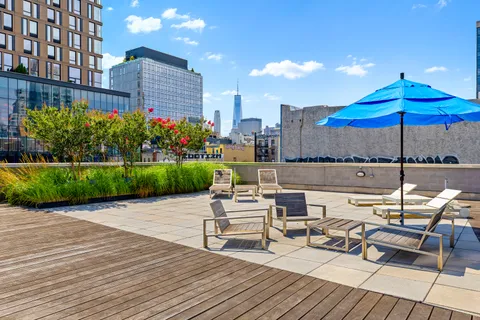 a view of a rooftop with chairs and umbrella in the patio