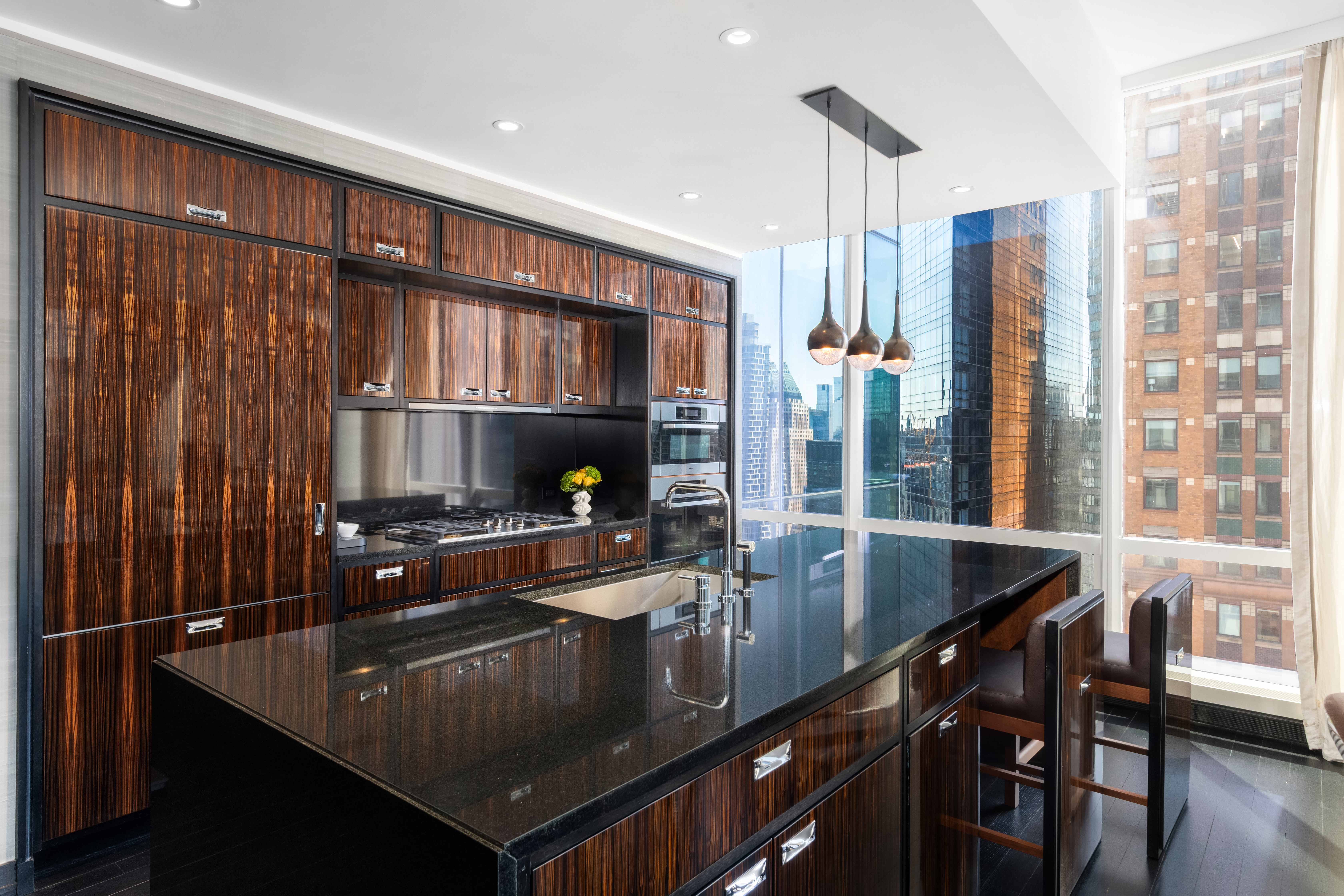 157 West 57th Street, Unit 50B Manhattan, NY 10019 - Photo 7 of 18 a kitchen with a sink a counter and chairs