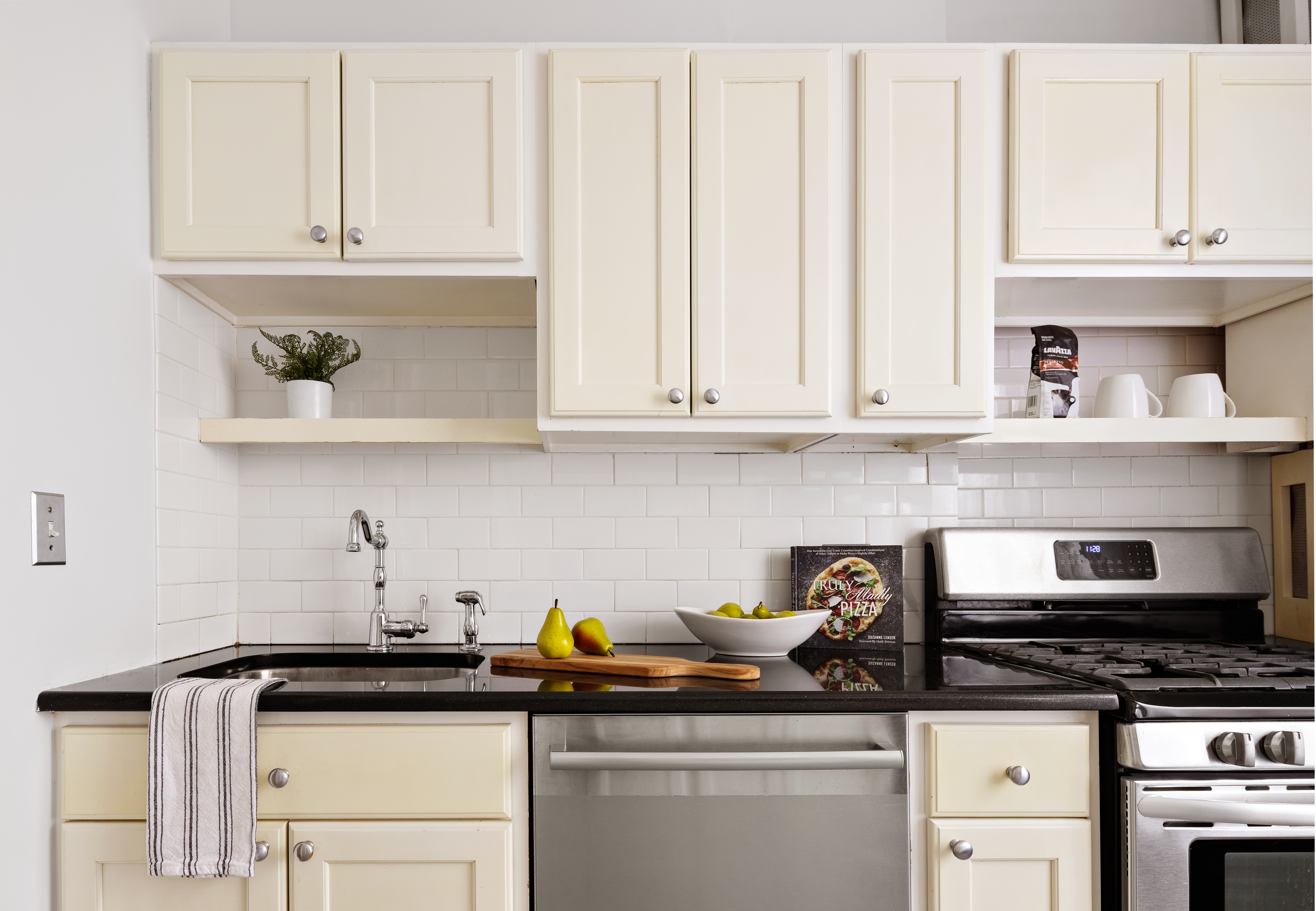 225 East 74th Street, Unit 6A Manhattan, NY 10021 - Photo 6 of 8 a kitchen with stainless steel appliances granite countertop a sink dishwasher stove and white cabinets