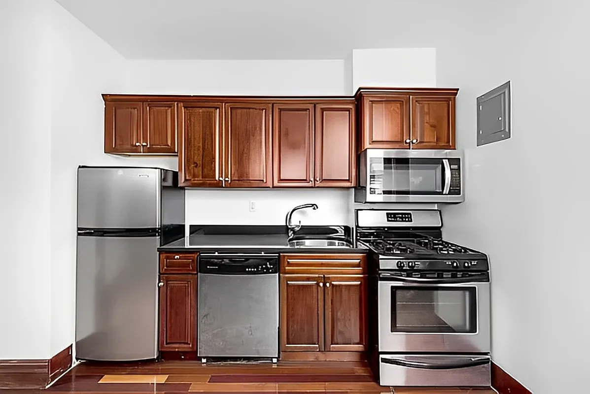 117 Mulberry Street, Unit 14 Manhattan, NY 10013 - Photo 2 of 4 a kitchen with granite countertop a refrigerator stove and microwave