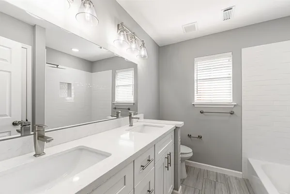 a bathroom with a double vanity sink a toilet and a window