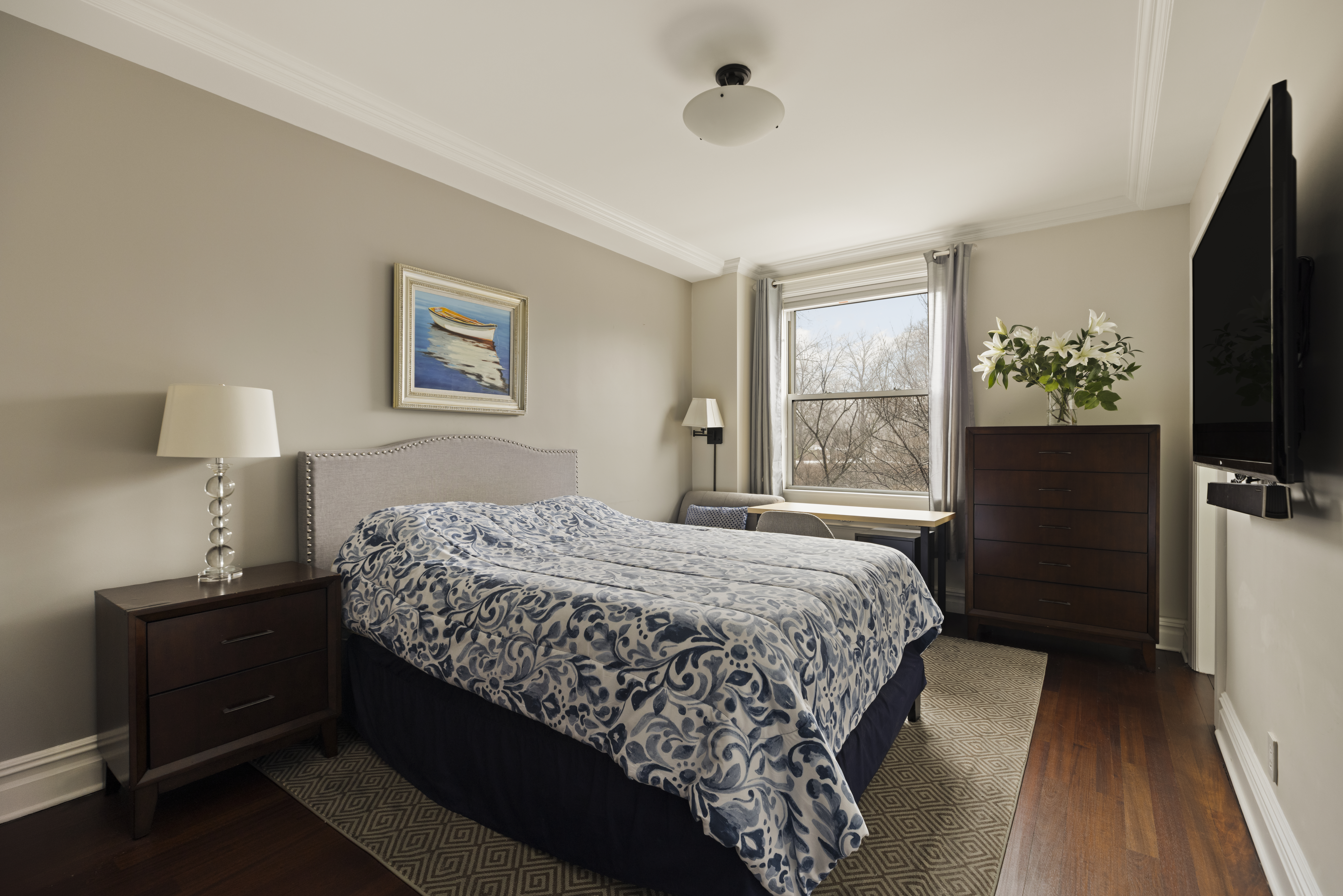 1158 5th Avenue, Unit 4A Manhattan, NY 10128 - Photo 10 of 23 a bedroom with a bed and a flat tv screen on a dresser