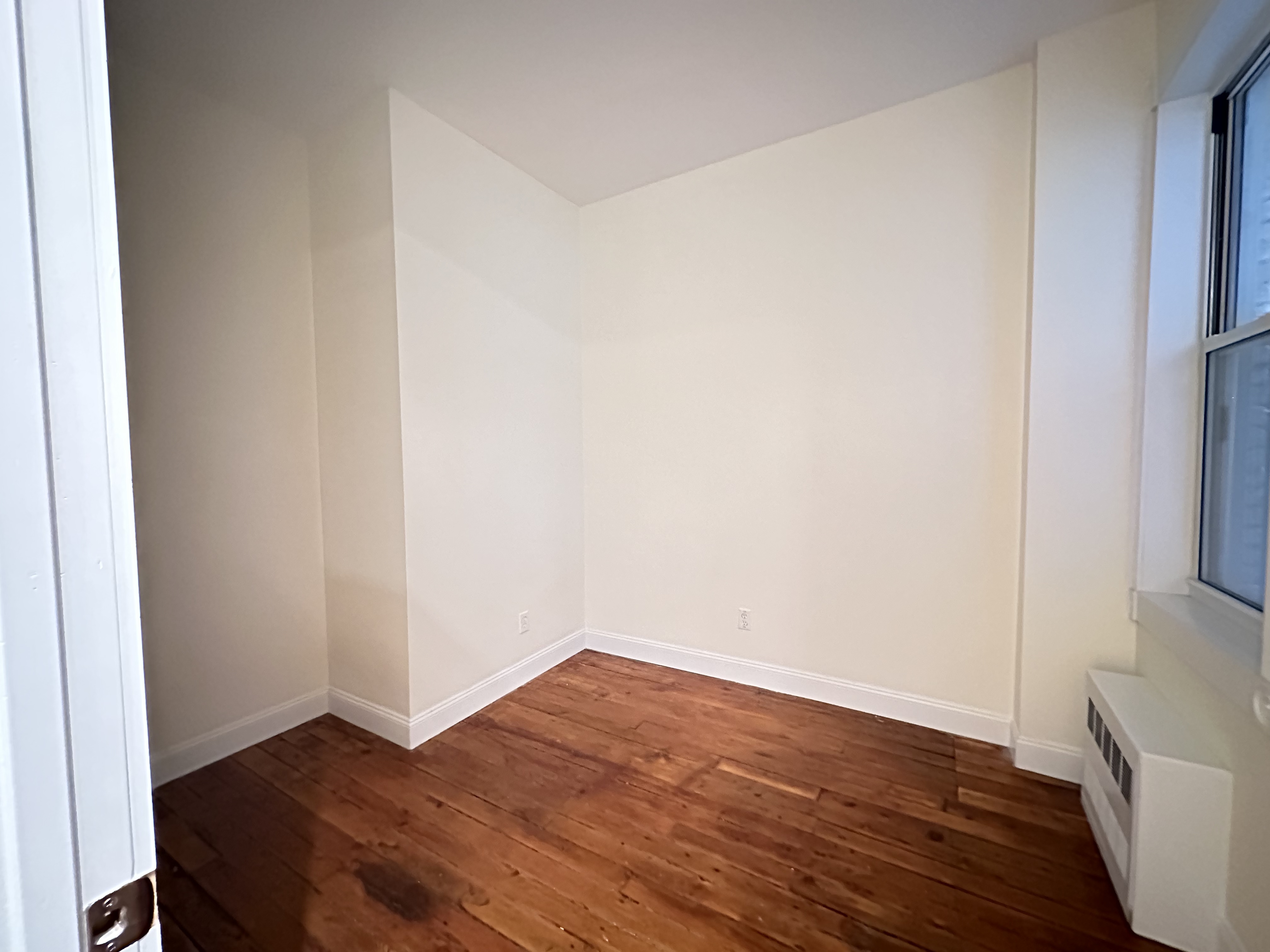 459 West 35th Street, Unit 1E Manhattan, NY 10001 - Photo 7 of 18 a view of an empty room with wooden floor and a window