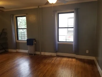 an empty room with wooden floor chandelier fan and windows
