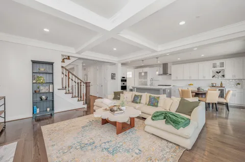 a kitchen with a dining table chairs wooden floor cabinets and appliances