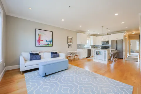 a living room with furniture and kitchen view with wooden floor