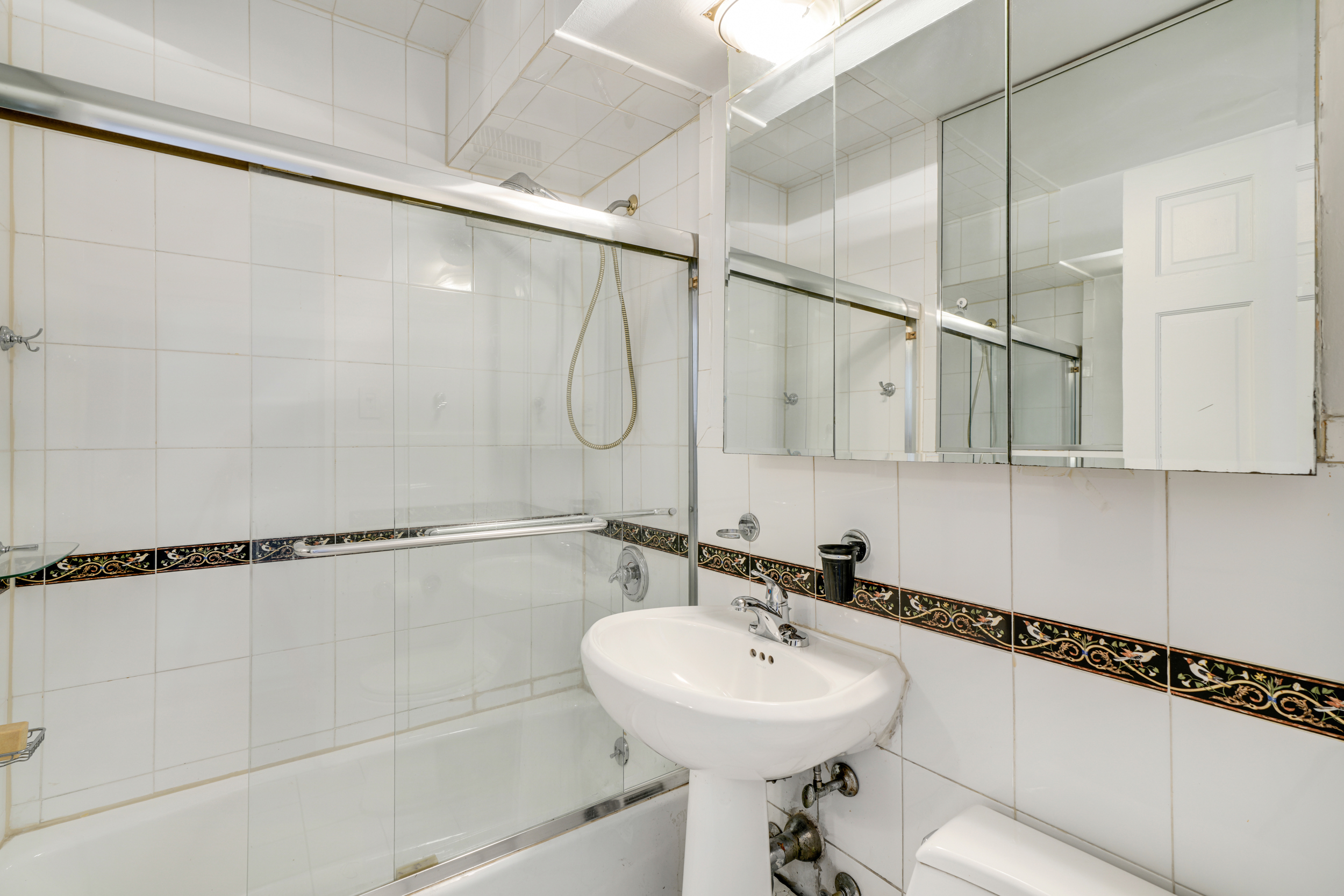 357 East 57th Street, Unit 5D Manhattan, NY 10022 - Photo 13 of 23 a bathroom with a sink mirror and shower