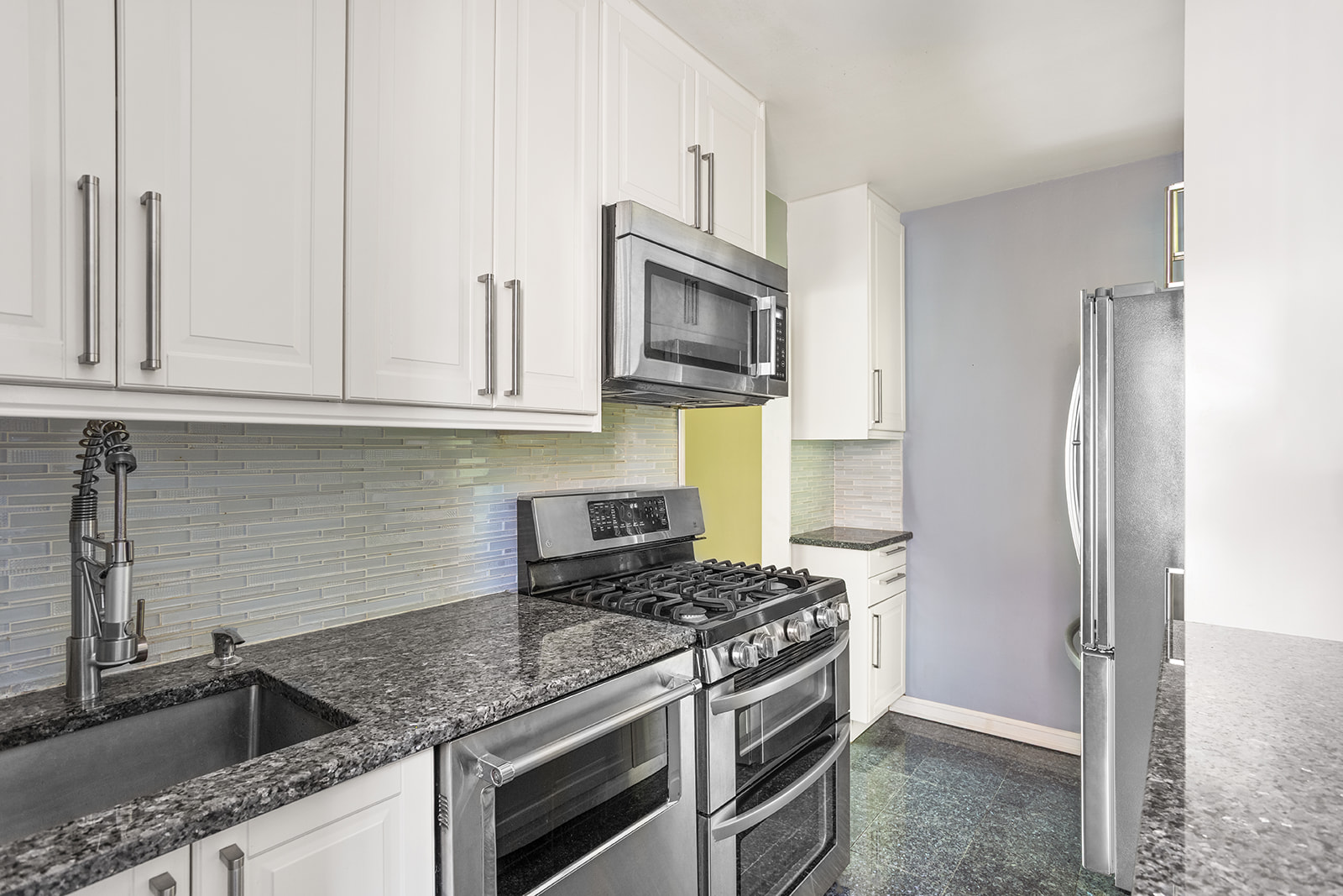 33-15 81st Street, Unit 4H Queens, NY 11372 - Photo 4 of 12 a kitchen with stainless steel appliances granite countertop a sink stove and refrigerator