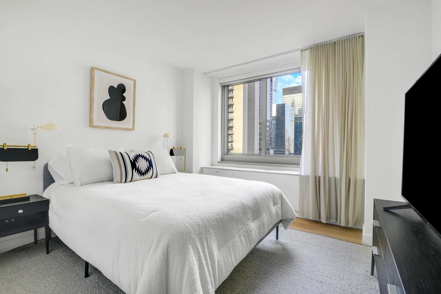 a bedroom with a bed and flat tv screen on the dresser