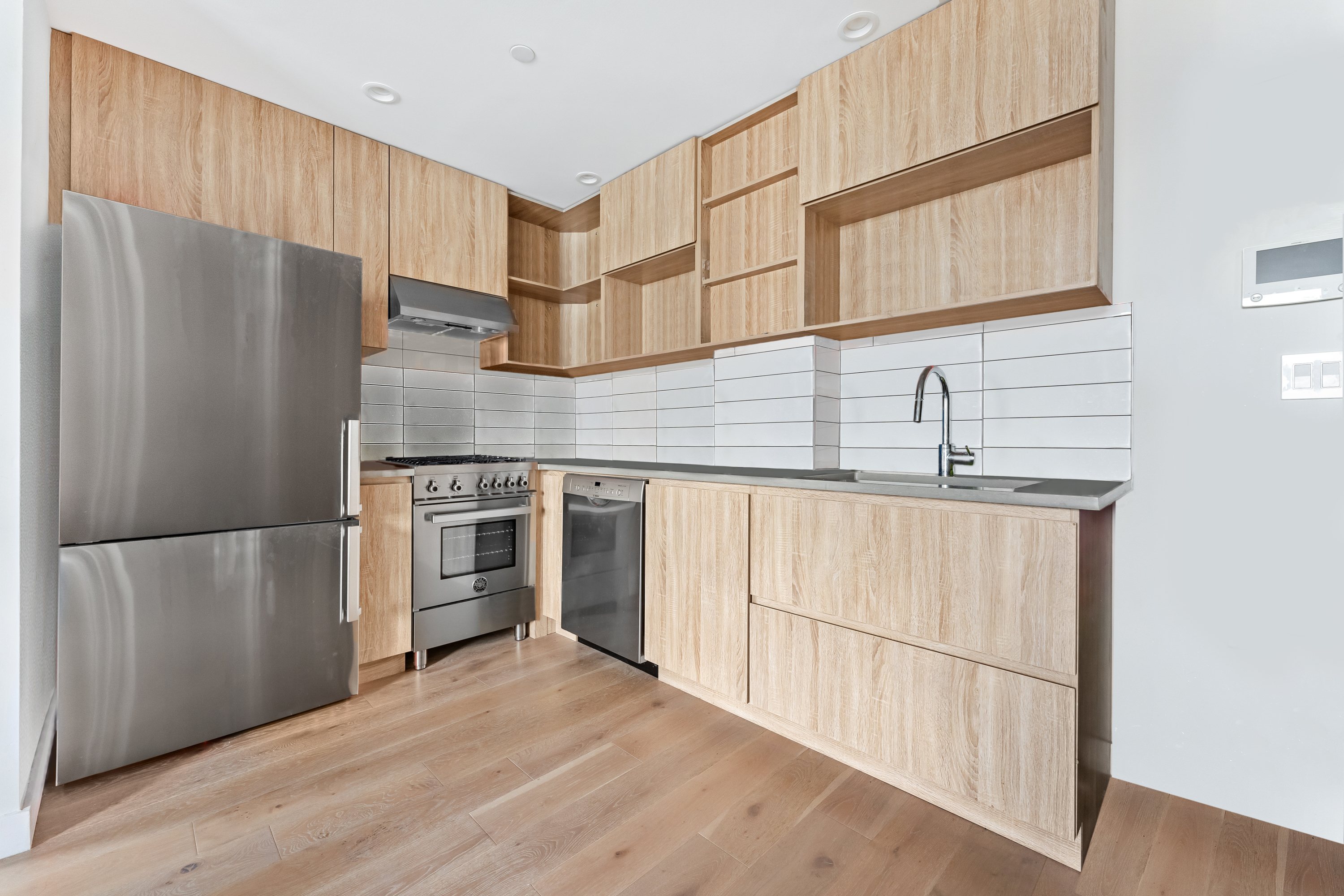 14-33 31st Avenue, Unit 5H Queens, NY 11106 - Photo 3 of 10 a kitchen with stainless steel appliances a refrigerator sink and cabinets
