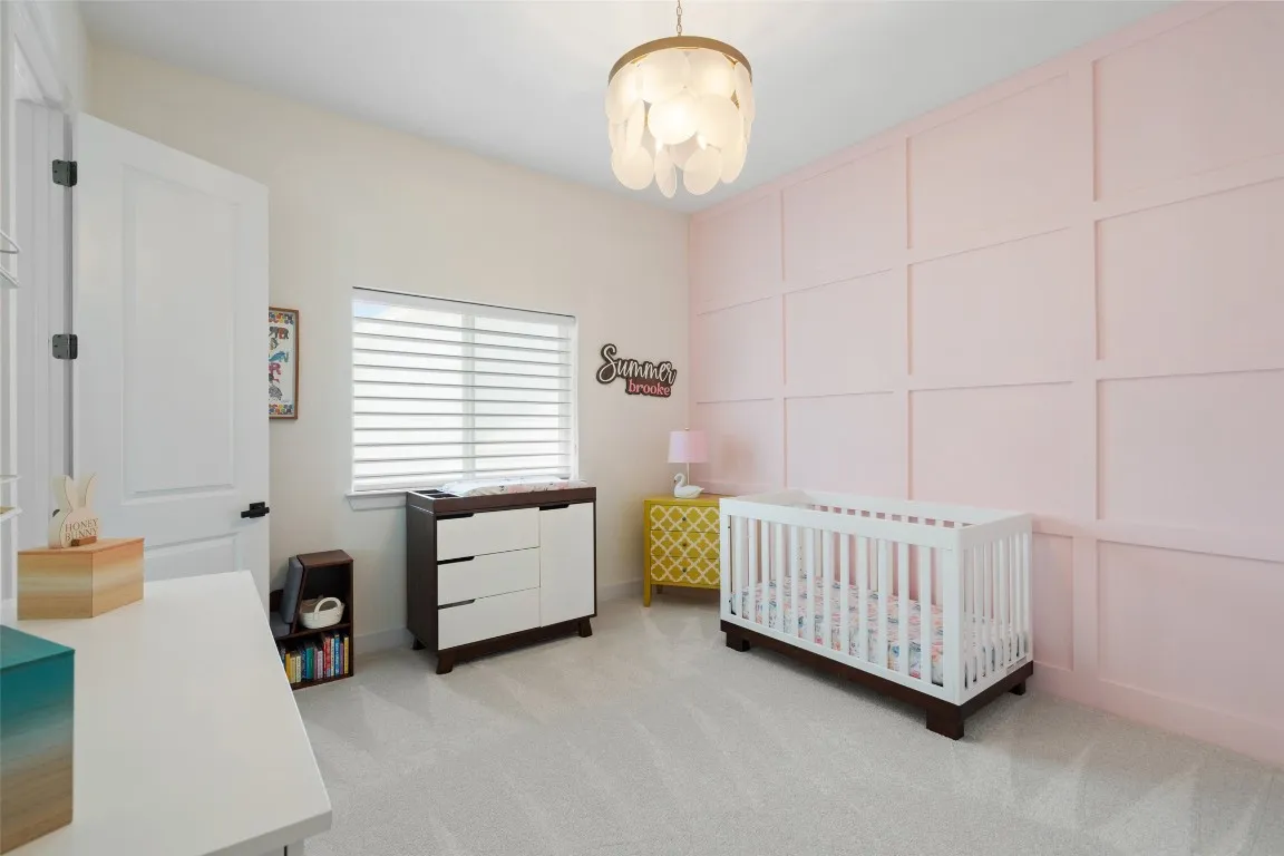 a bedroom with a baby bed a chandelier and a window