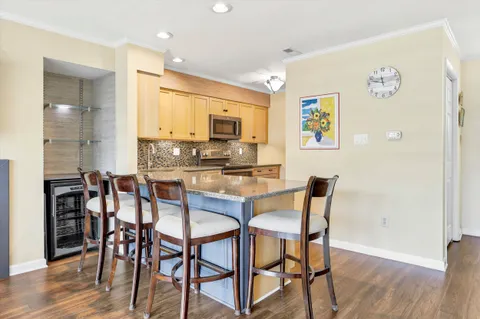 a kitchen with stainless steel appliances kitchen island granite countertop a dining table chairs and a refrigerator