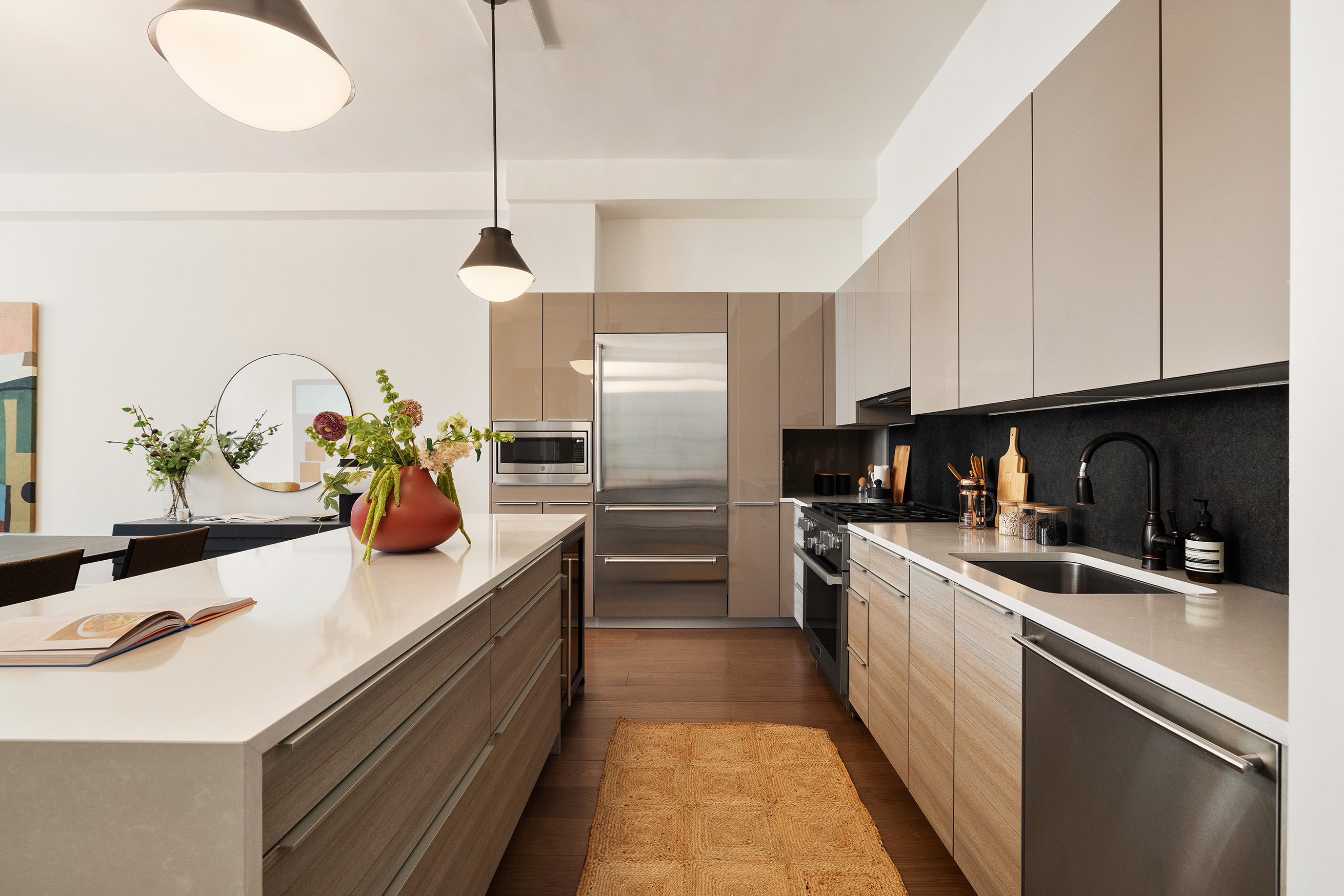 42 East 20th Street, Unit 4AD Manhattan, NY 10003 - Photo 4 of 19 a kitchen with stainless steel appliances a sink a stove top oven a chimney cabinets and a dining table