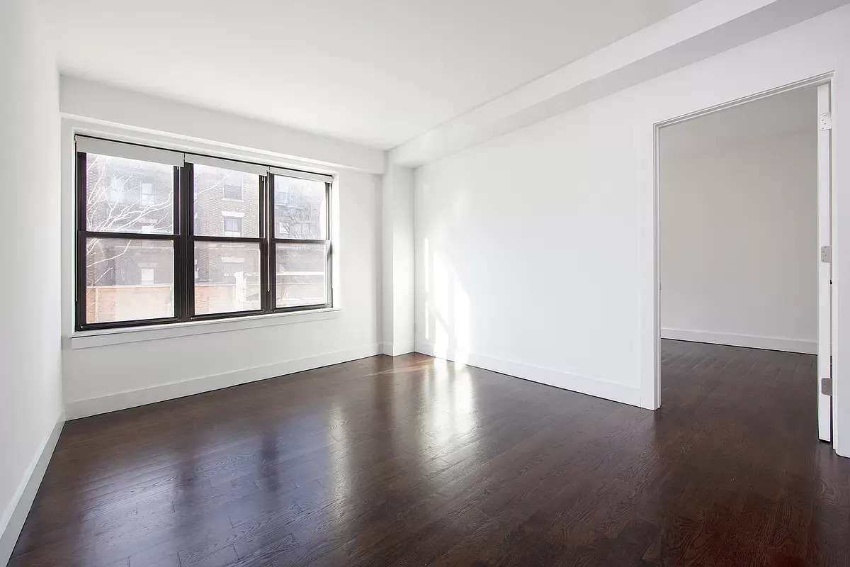 341 Eastern Parkway, Unit 5E Brooklyn, NY 11216 - Photo 2 of 8 a view of an empty room with wooden floor and a window