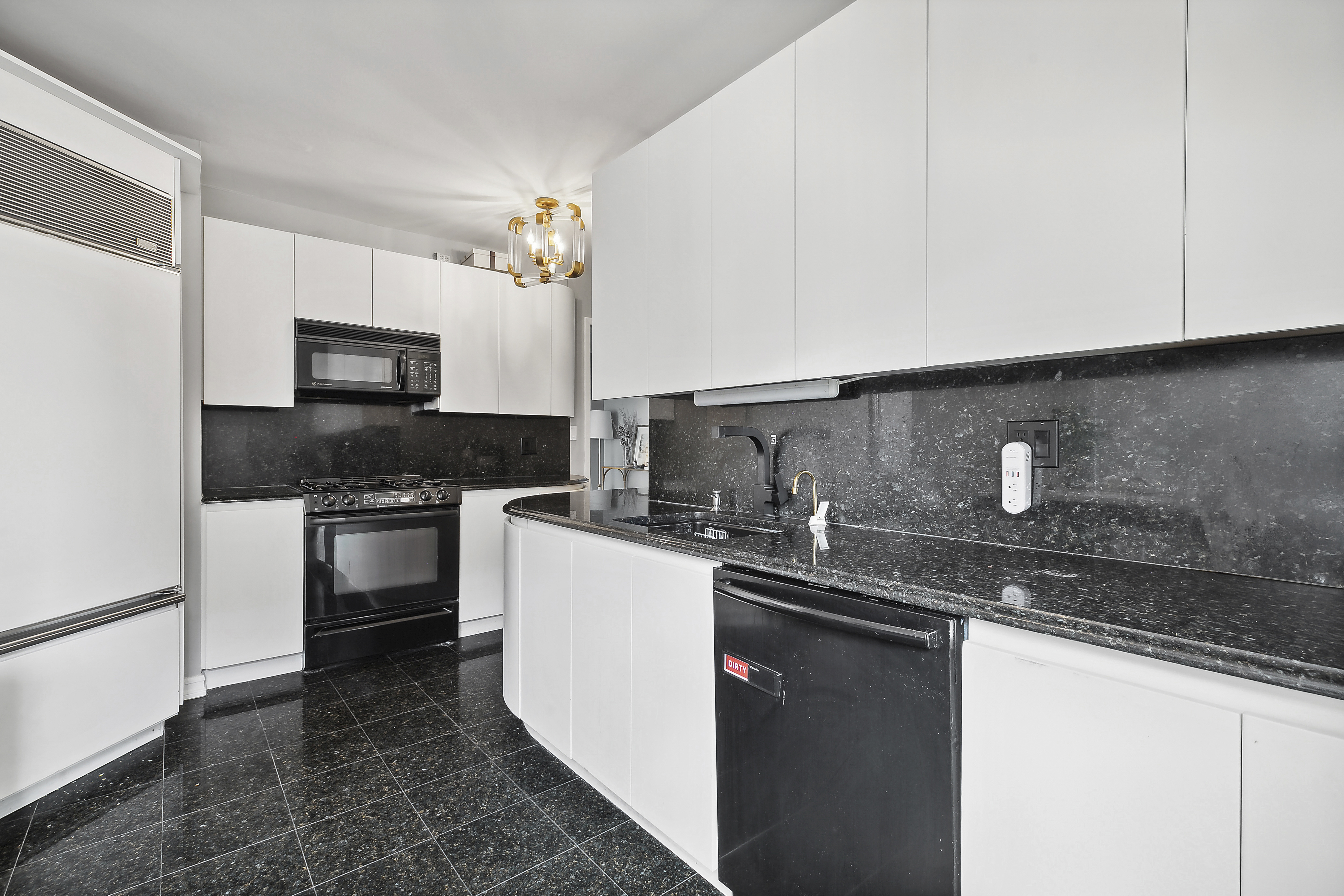 303 East 57th Street, Unit 11L Manhattan, NY 10022 - Photo 8 of 11 a kitchen with stainless steel appliances granite countertop a sink stove and microwave
