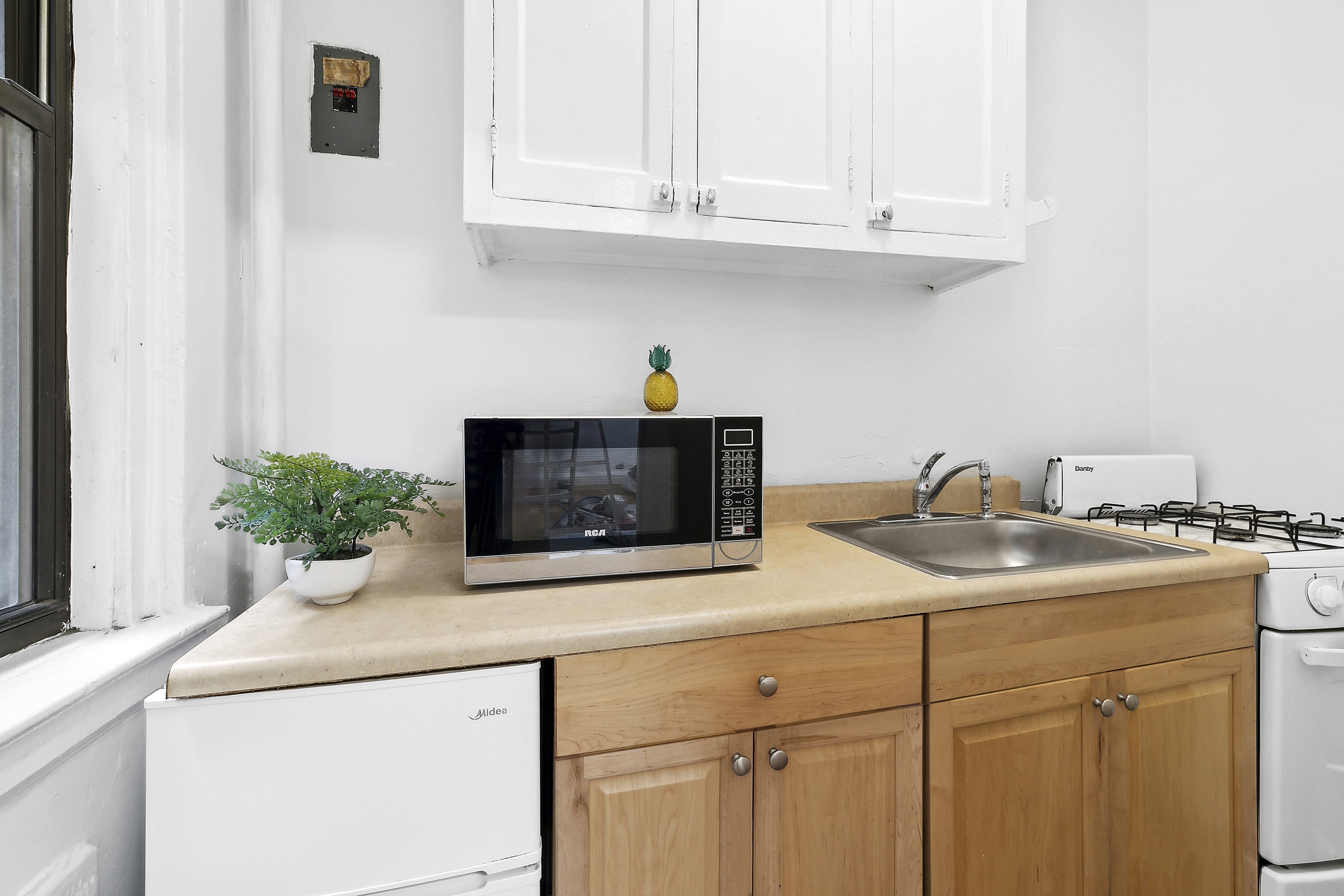 321 East 54th Street, Unit 1D Manhattan, NY 10022 - Photo 3 of 9 a kitchen with stainless steel appliances white cabinets and a sink