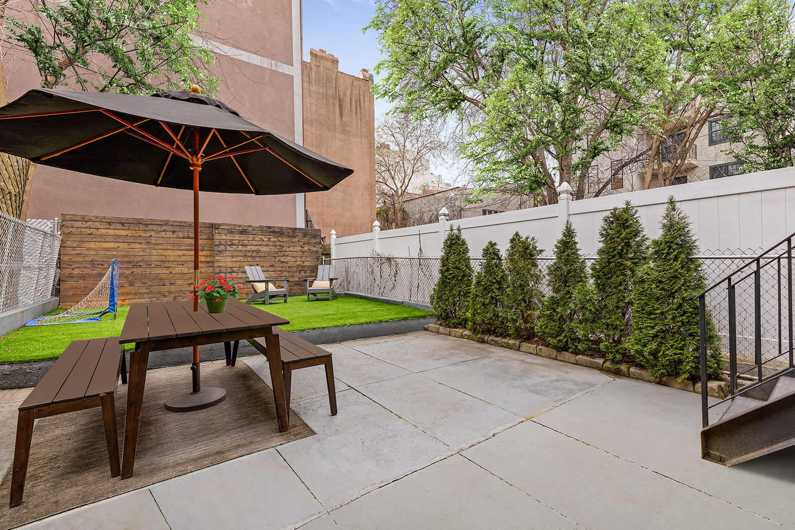a backyard of a house with table and chairs under an umbrella