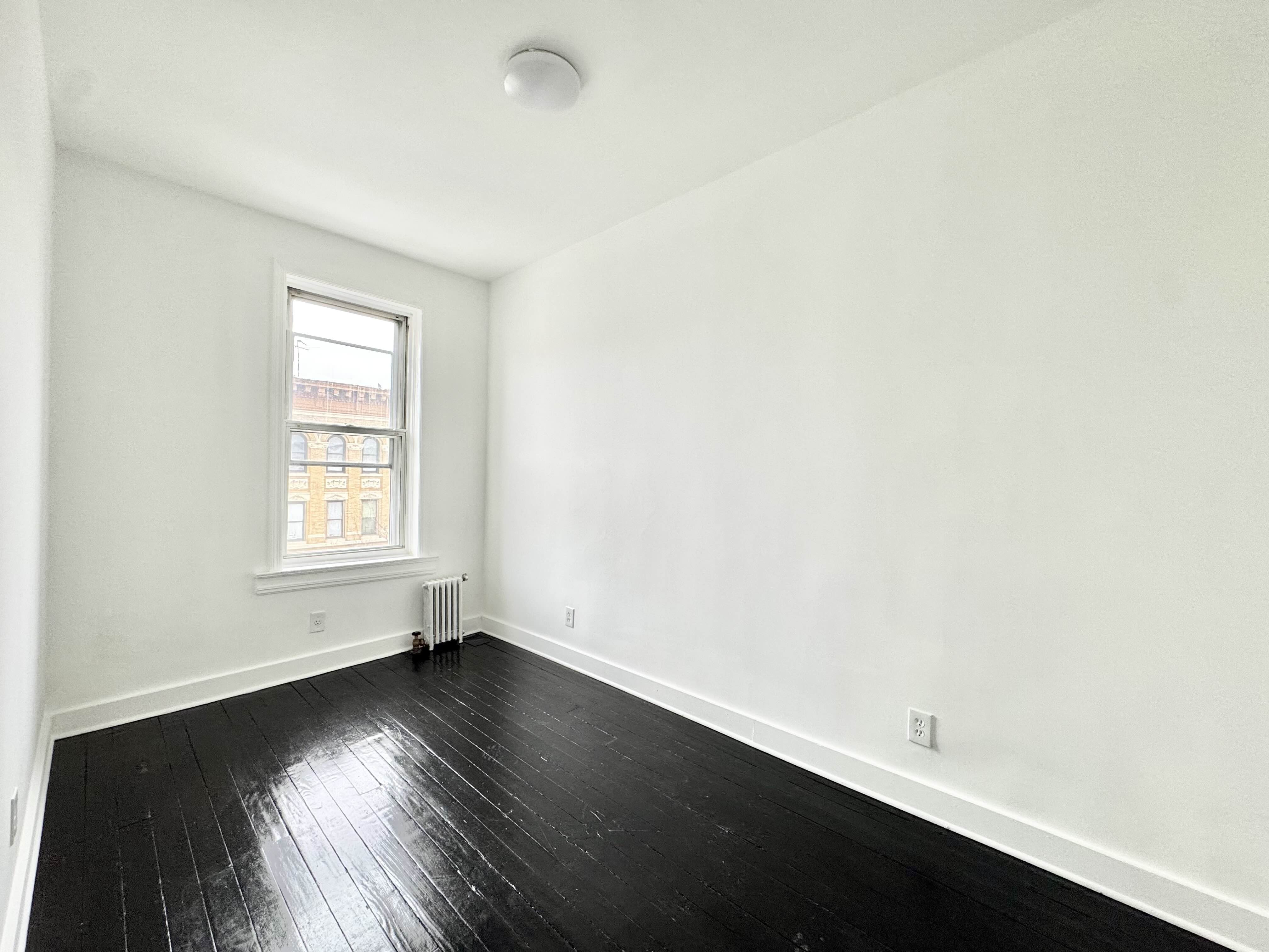 406 Rogers Avenue, Unit 3 Brooklyn, NY 11225 - Photo 6 of 9 an empty room with wooden floor and windows