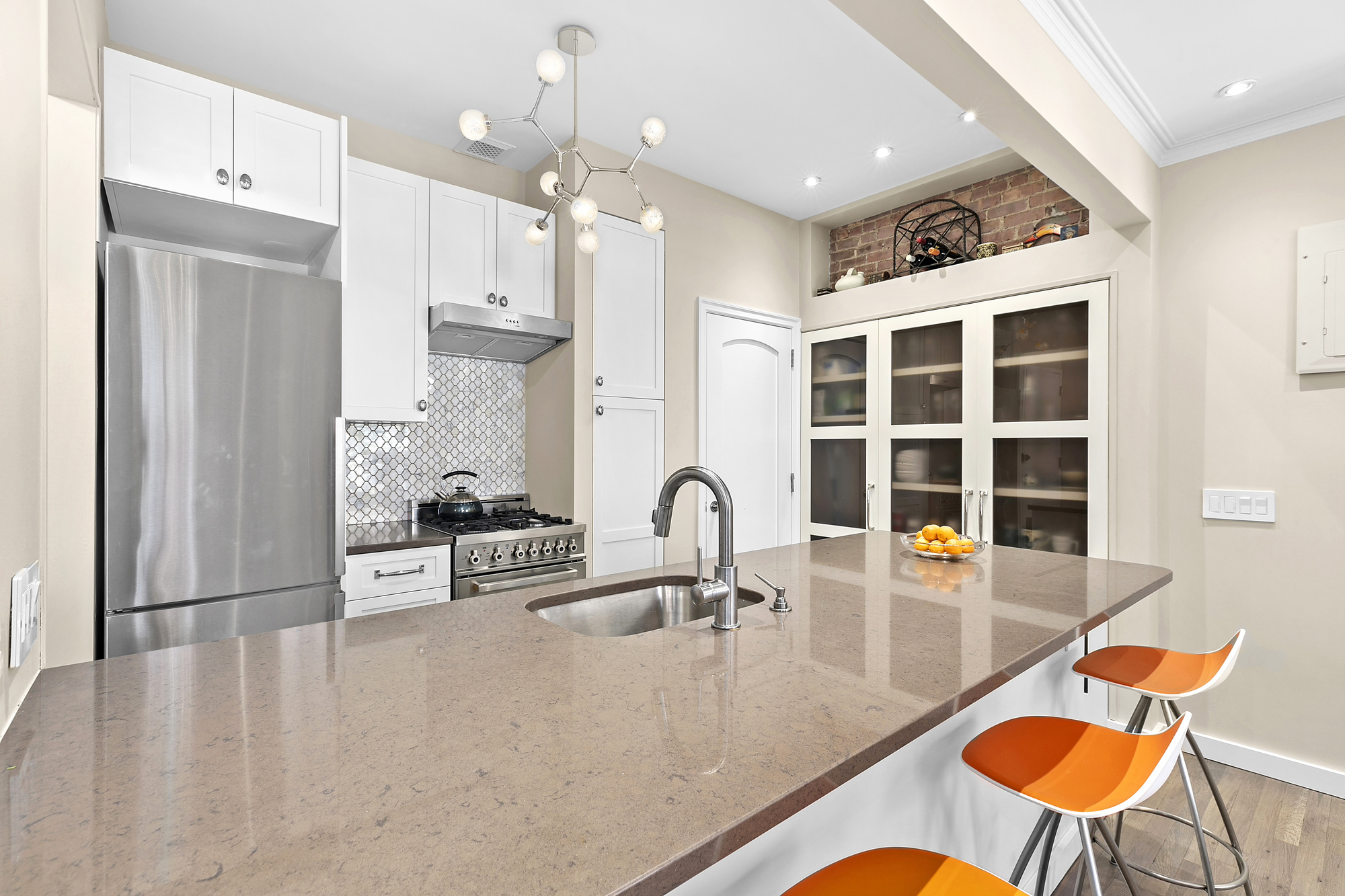 450 West 23rd Street, Unit E Manhattan, NY 10011 - Photo 4 of 12 a kitchen with stainless steel appliances granite countertop a dining table chairs and sink
