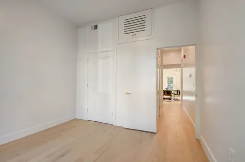 an empty room with wooden floor and bathroom view