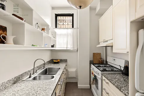 a kitchen with white cabinets a sink stove and refrigerator