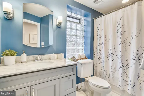 a bathroom with a granite countertop sink a toilet and a mirror