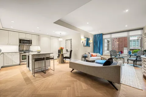 a living room with furniture and kitchen view with wooden floor