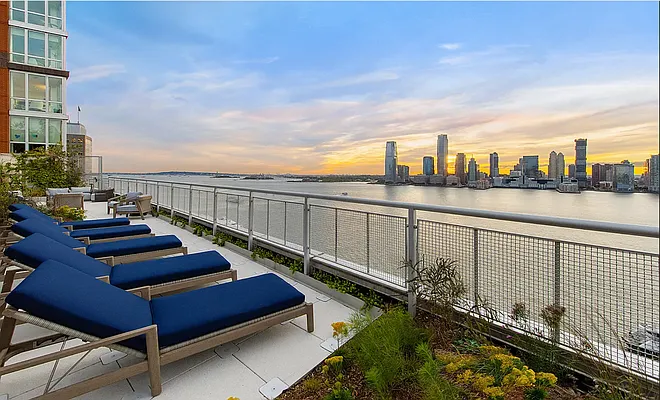 20 River Terrace, Unit 22A Manhattan, NY 10282 - Photo 21 of 27 a view of roof deck with two chairs and wooden fence