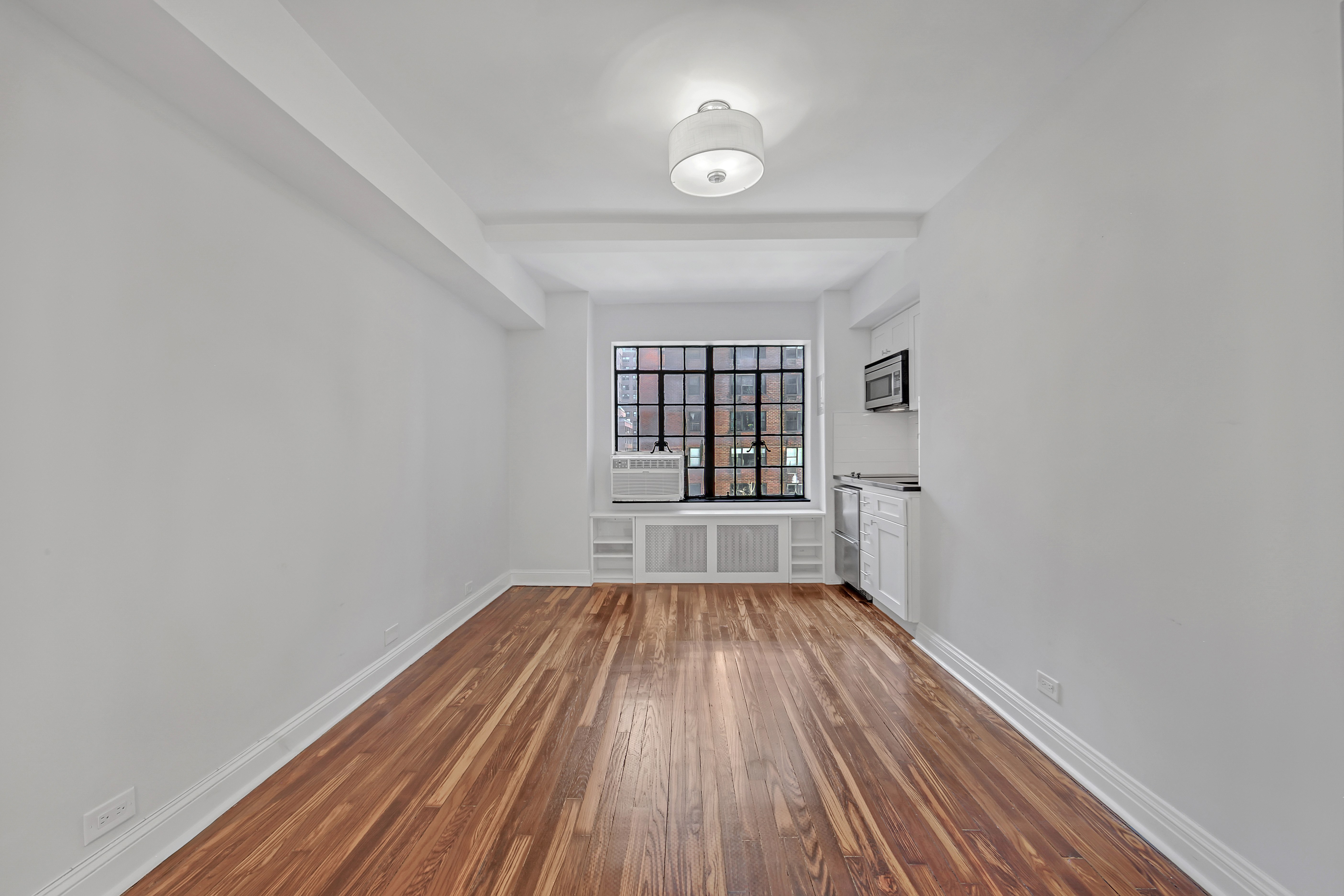 5 Tudor City Place, Unit 608 Manhattan, NY 10017 - Photo 3 of 12 wooden floor in a empty room with a window
