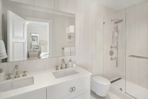 a bathroom with a toilet a sink a mirror a shower and vanity