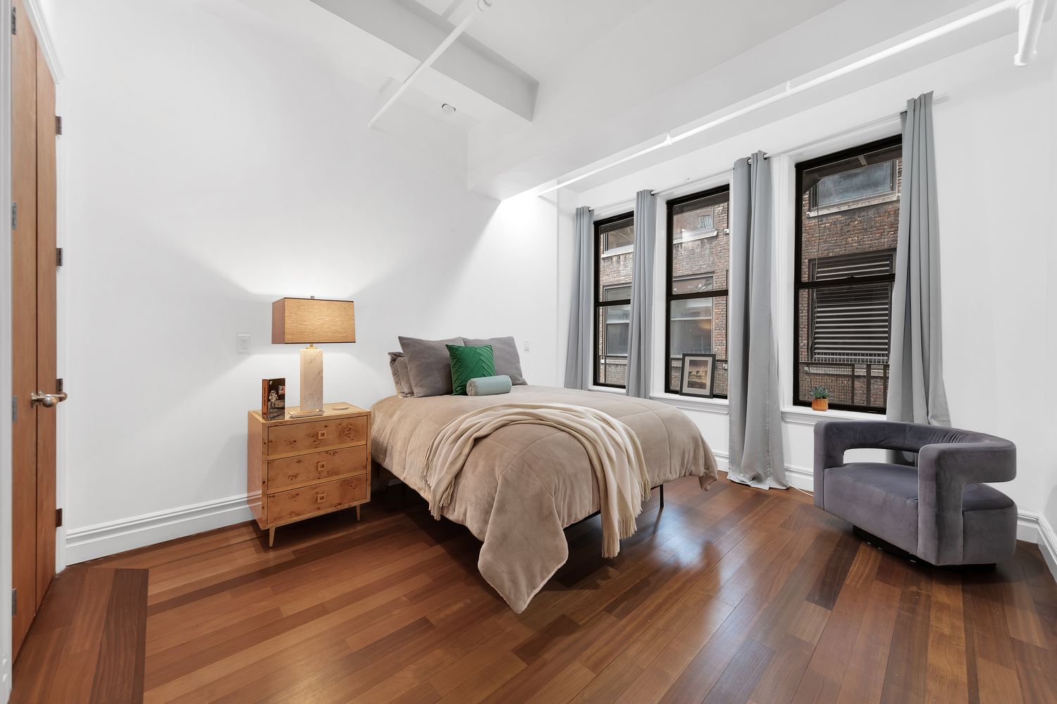 a spacious bedroom with a bed and wooden floor