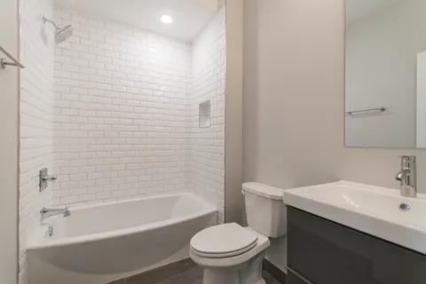 a bathroom with a bathtub shower sink vanity and toilet