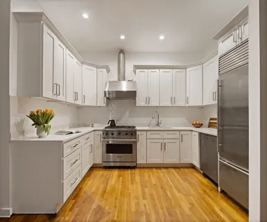 a kitchen with stainless steel appliances granite countertop a stove top oven a sink and dishwasher with white cabinets