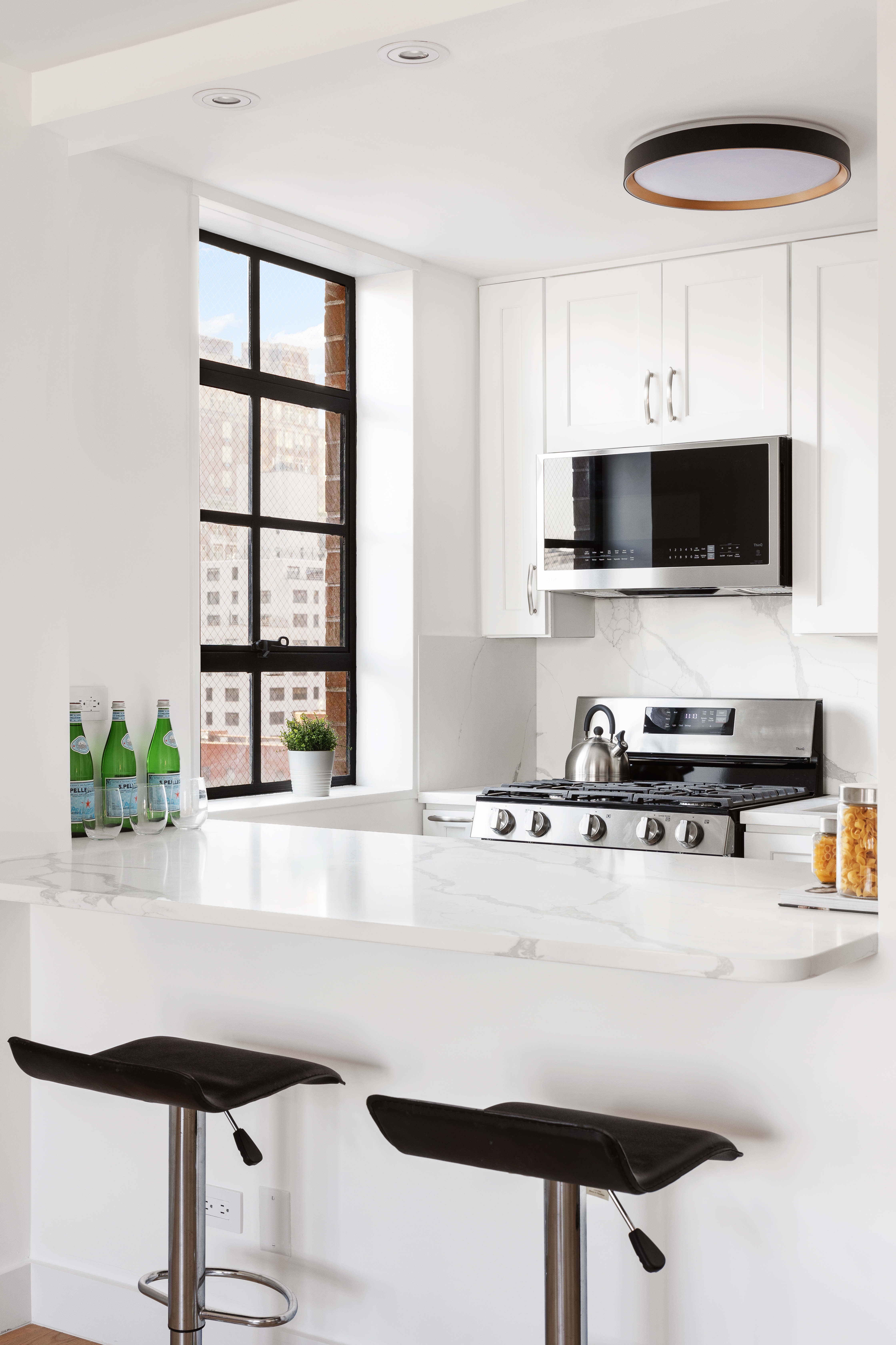 200 East 90th Street, Unit 12F Manhattan, NY 10128 - Photo 10 of 13 a kitchen with stainless steel appliances a stove a sink and a microwave