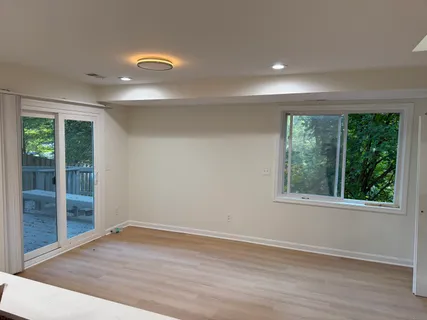 a view of an empty room with wooden floor and a window