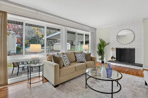 a living room with furniture a fireplace a flat screen tv and a large window
