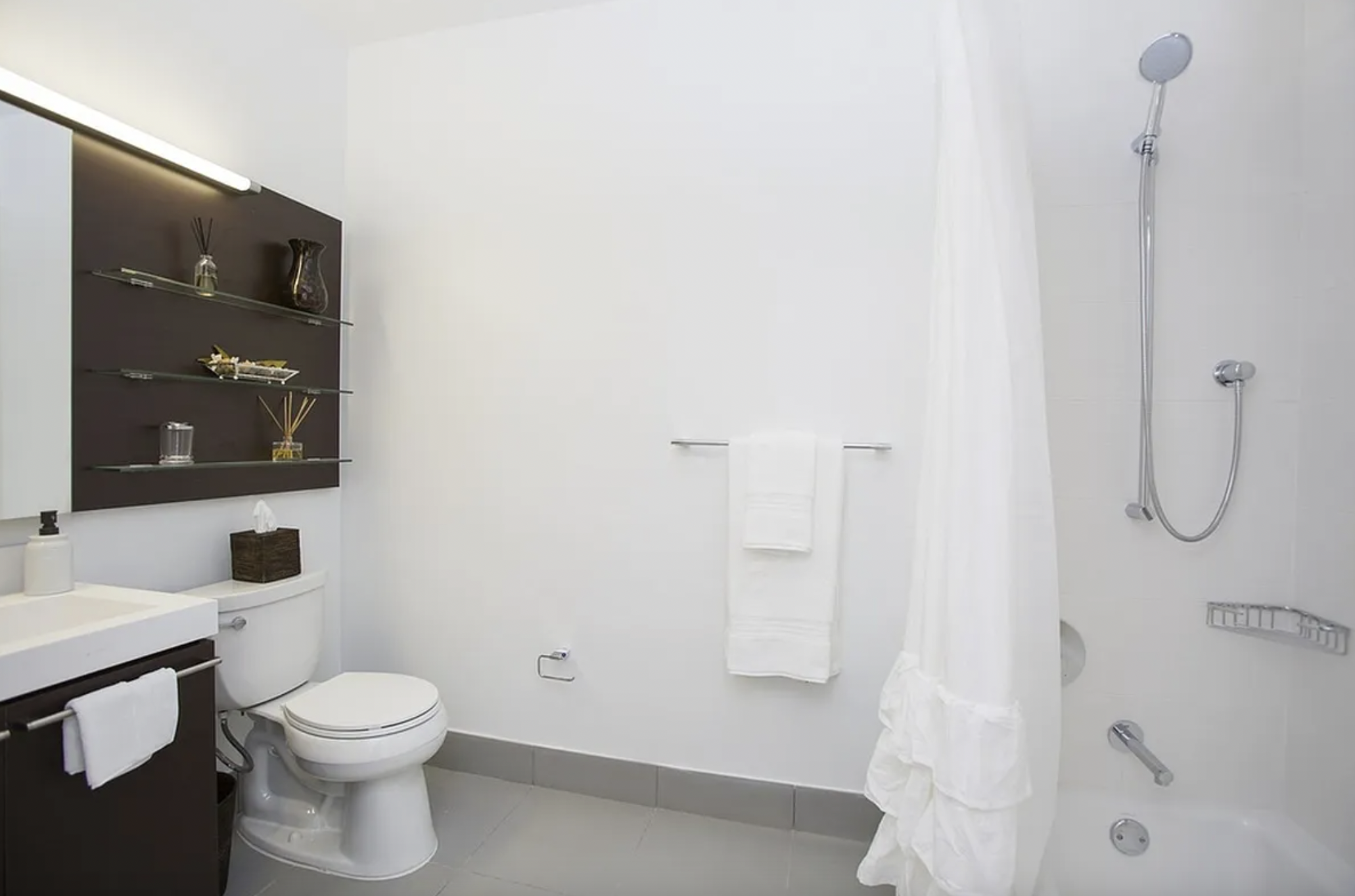 43-25 Hunter Street, Unit 4312W Queens, NY 11101 - Photo 4 of 16 a white toilet sitting next to a bathroom sink and a shower