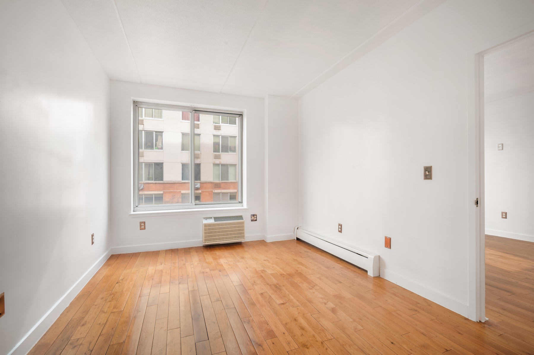 29 West 138th Street, Unit 2D Manhattan, NY 10037 - Photo 4 of 10 an empty room with wooden floor and windows